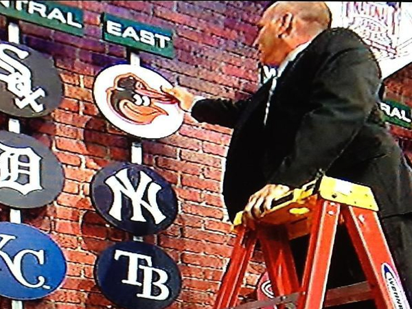 man hanging orioles logo along with other teams logos on wall