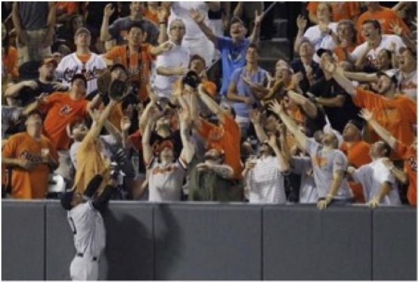 crowd in stands trying to catch baseball with baseball player