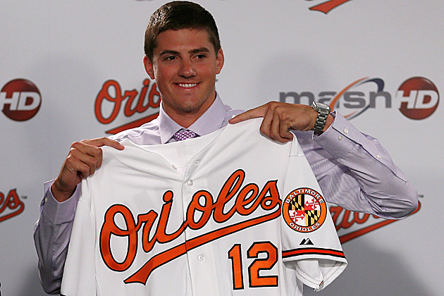 baseball player holding up orioles jersey in front of his chest