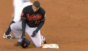 orioles player kneeled down by base holding hat in hand