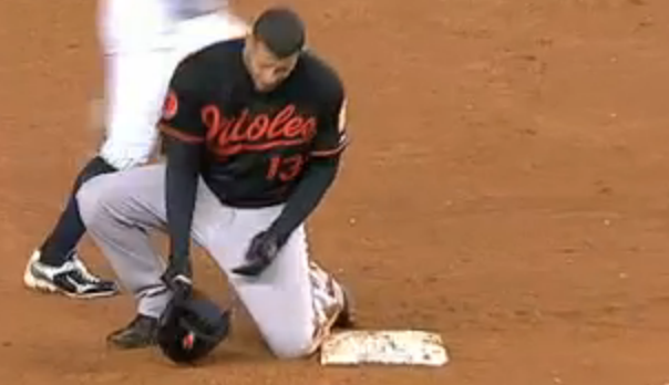 orioles player kneeled down by base holding hat in hand