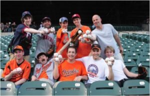 group of orioles fans in stands holding baseballs