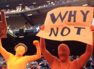 two people dressed in orange and yellow body suits holding up sign