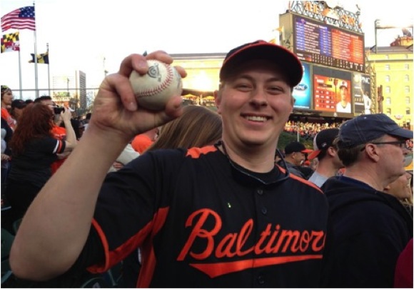 guy holding baseball in hand with orioles jersey on