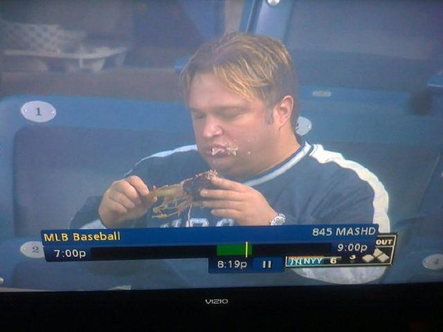 still shot of yankee fan on tv eating turkey leg in stands