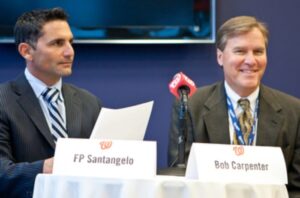 two men in suits sitting next to each other in front of microphone