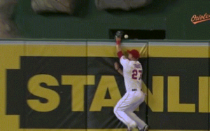 baseball player jumping up to catch ball