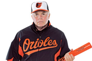 buck showalter posing holding orange baseball bat with serious look on face