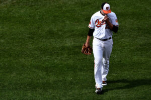 orioles player holding shirt up to mouth with head down walking away