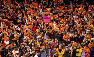 orioles fans in stands wearing orange and holding up signs