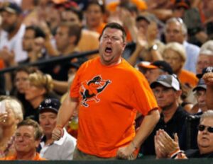 man standing up in stands with arms out to side yelling
