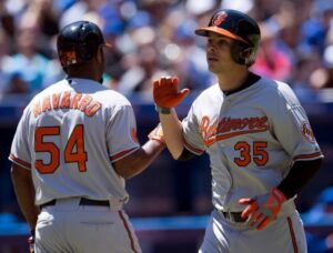 two players for orioles passing by each other arms up