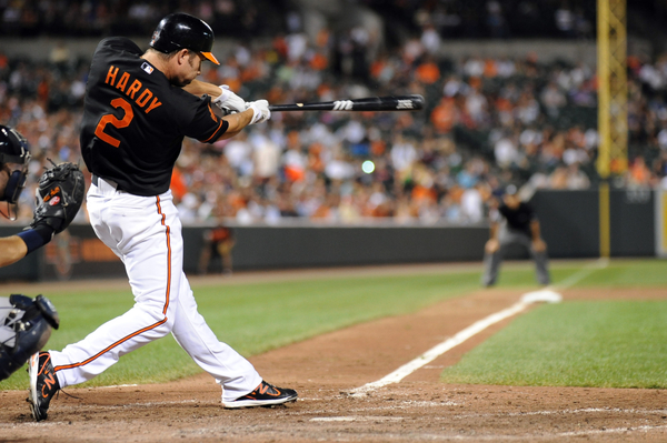 orioles player hardy with bat extended after hitting baseball at home plate