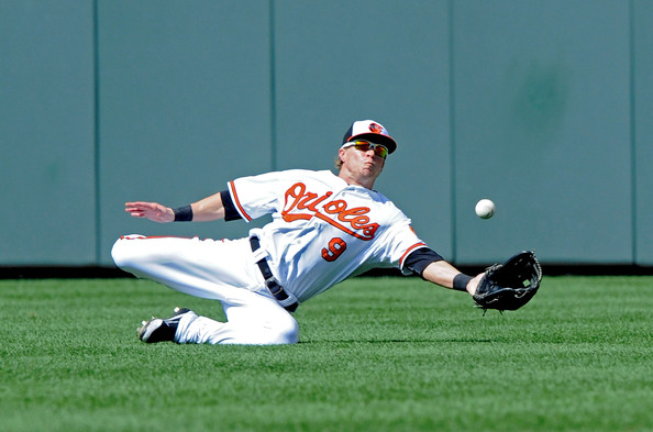 orioles player sliding down while trying to catch baseball