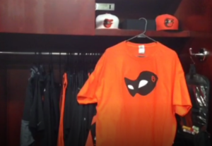 orange orioles shirt hanging next to hats in closet