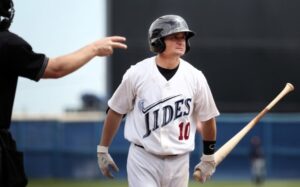 baseball player holding bat with disgruntled look with referee pointing two fingers