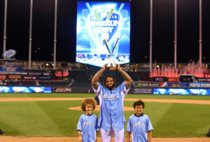 guy holding up baseball plaque with two kids standing on either side