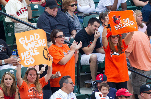 orioles fans in stands holding signs and flags