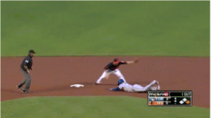 baseball player sliding into base with referee standing by