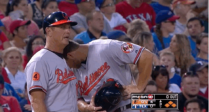 oriole player with head down resting on teammates shoulder