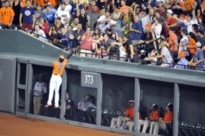 orioles player jumping up to catch baseball by where fans are sitting