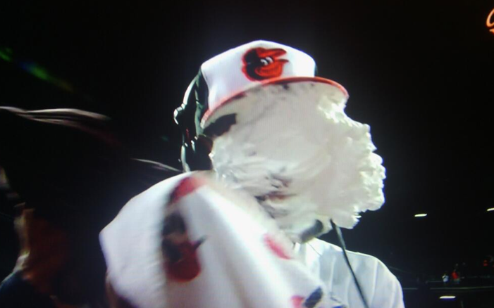 person wearing orioles hat with pie all over face