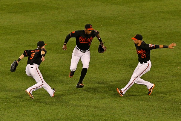 three orioles players with arms extended about to jump up together