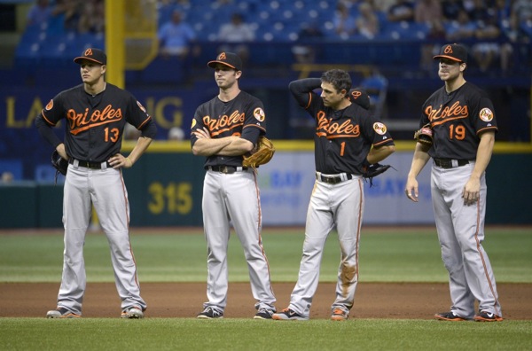 four orioles players standing in a line on baseball field