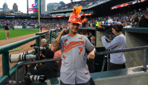 orioles fan standing in front of photographers during game