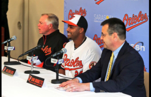 orioles manager player and man in suit sitting at press conference table