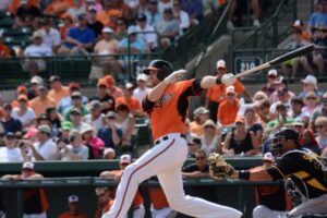 player after hitting baseball with catcher behind him