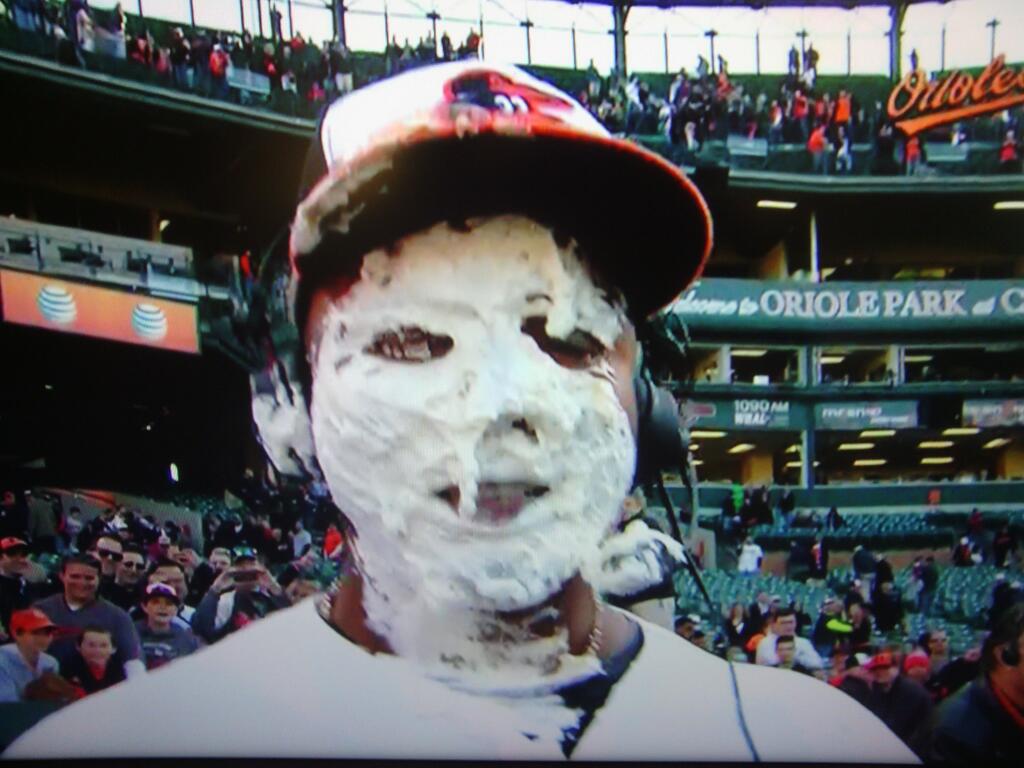 guy wearing orioles hat and headset with pie all over face