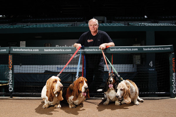 buck showalter standing behind fence with his four dogs in front of him