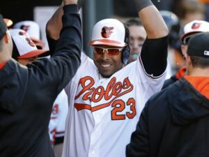 orioles player in dugout with arms up surrounded by other players