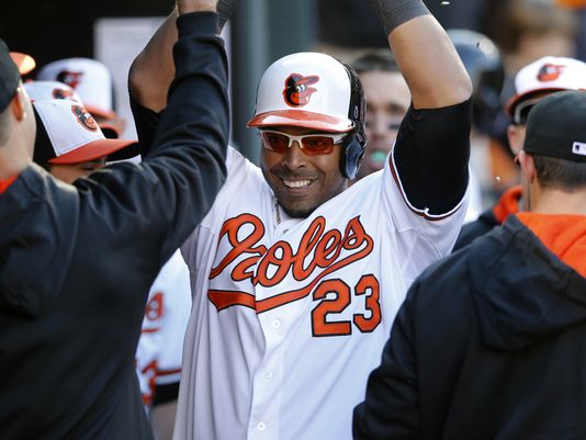 orioles player in dugout with arms up surrounded by other players