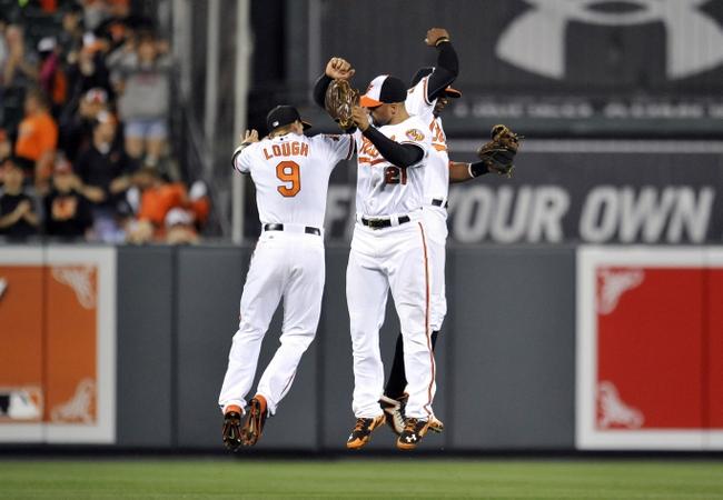 three orioles players jumping up with each other out on field