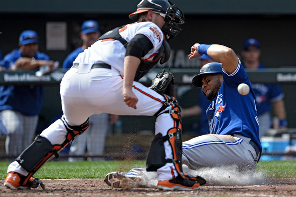 blue jays player sliding into home base by orioles catcher