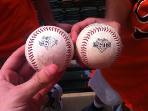 two fans holding up two baseballs side by side