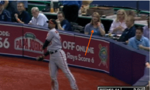 orange arrow pointing at woman sitting behind orioles player