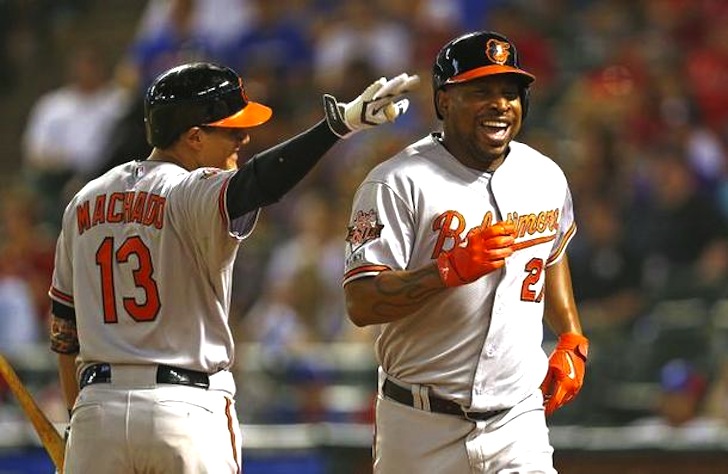two orioles players smiling one running by the other