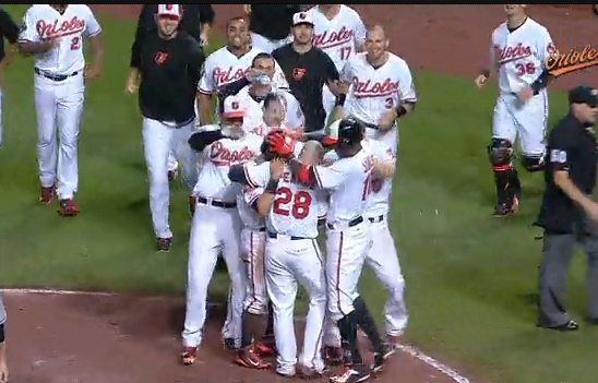 orioles players in a huddle on field after winning