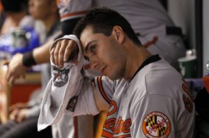 orioles player in dugout wiping forehead with towel on arm