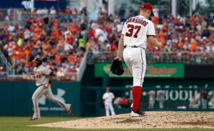 pitcher standing on mound with orioles player running by in background