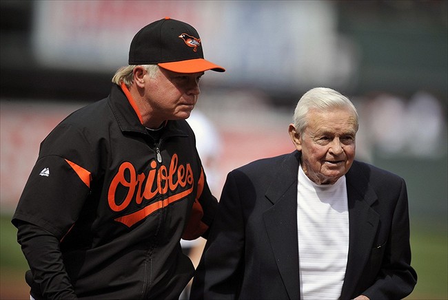 orioles manager with hand on older mans back while walking