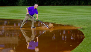 guy pushing mud on baseball diamond