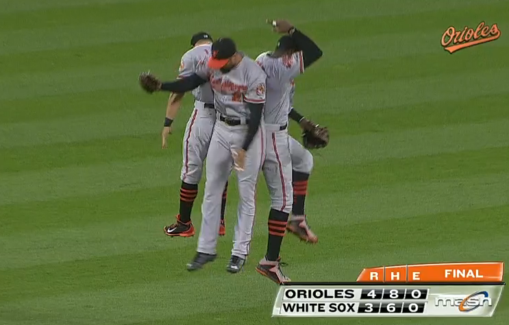 three orioles players jumping up backs to each other celebrating