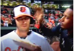 guy with headset on and orioles gear about to have pie thrown in face