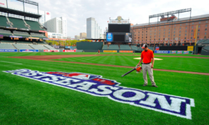 guy holding blower in hand standing by postseason drawing on field