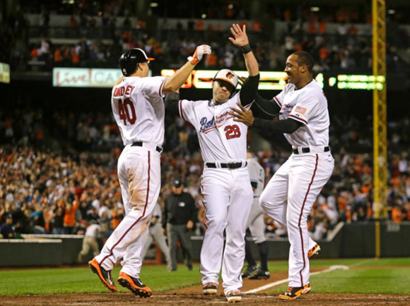three orioles players with hands up celebrating on field