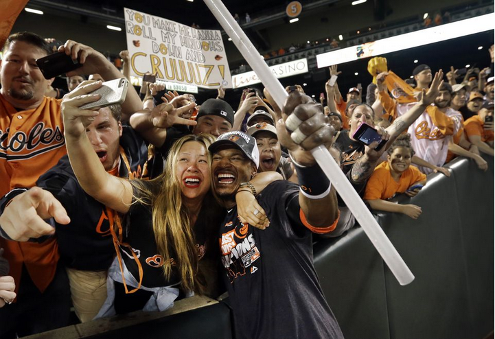 woman taking selfie with orioles player and fans in stand